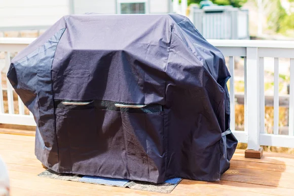 Abgedeckter Gasgrill auf Holzterrasse